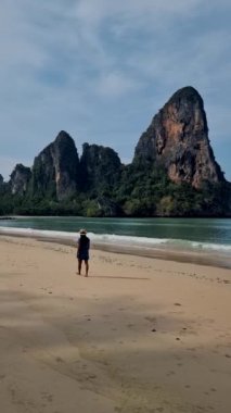 Railay Beach Krabi Tayland 'da yürüyen bir kadın, kumsaldaki tropik Railay Krabi plajı, Tayland' daki huzurlu Railay Plajı manzaralı geleneksel uzun bir tekne.. 