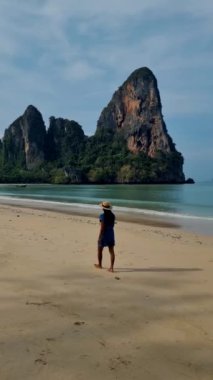 Railay Beach Krabi Tayland 'da yürüyen kadınlar, plajda gezen Railay Krabi' nin tropikal plajı, Tayland 'da geleneksel uzun bir teknesi olan huzurlu Railay Railay Plajı manzarası.. 