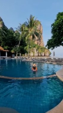 Tayland 'da lüks bir oteldeki yüzme havuzunda bir çift kadın ve erkek. Railay Beach Krabi 'de sandalyeli ve şemsiyeli lüks havuz.