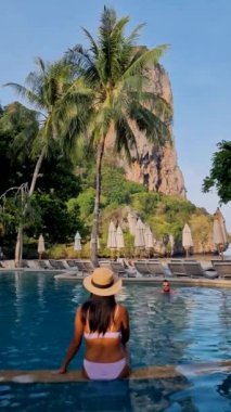 Tayland 'da lüks bir oteldeki yüzme havuzunda bir çift kadın ve erkek. Railay Beach Krabi 'de sandalyeli ve şemsiyeli lüks havuz.