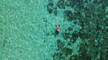 Mercan resifinde yüzen Asyalı kadınlar, Tayland 'ın Trang kentindeki Koh Kradan adasının havadan görünüşü. Mercan resifi ve turkuaz renkli okyanus drone manzaralı tropik plaj.