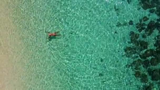 アジアの女性がサンゴ礁で泳いでいる タイのトランプにあるKoh Kradan島の空中ビュー サンゴ礁とターコイズブルーの海の見える熱帯のビーチ上からのドローンの眺め — ストック動画