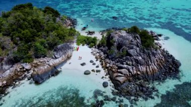 Birkaç erkek ve kadın Koh Lipe Tayland 'da tatildeler. Uzun kuyruklu tekneler ve kanolar Kla Adası' nın Koh Lipe kentindeki küçük bir adada.