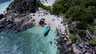 Birkaç erkek ve kadın Koh Lipe Tayland 'da tatildeler. Uzun kuyruklu tekneler ve kanolar Kla Adası' ndaki Koh Lipe adasının önündeki küçük bir adada.