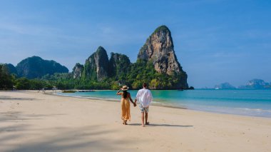 Railay Beach Krabi Tayland, Railay Krabi 'nin tropikal plajı, kumsalda bir çift kadın ve erkek, Tayland' da geleneksel uzun bir teknesi olan huzurlu Railay Kumsalı manzarası.. 