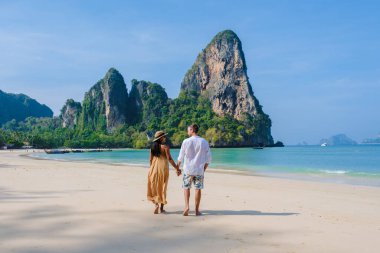 Railay Beach Krabi Tayland, Railay Krabi 'nin tropikal plajı, kumsalda bir çift kadın ve erkek, Tayland' da geleneksel uzun bir teknesi olan huzurlu Railay Kumsalı manzarası.. 