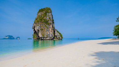 Railay Plajı Krabi Tayland, Tayland 'da geleneksel uzun teknesi ve bulutlu gökyüzü olan huzurlu Railay Krabi' nin tropikal plajı.