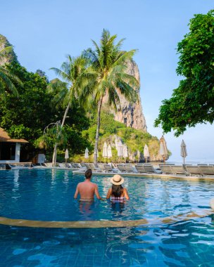 Tatil sırasında Tayland 'da lüks bir tatil köyünde yüzme havuzunda birkaç erkek ve kadın. 