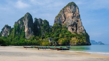 Railay Plajı Krabi Tayland, Tayland 'da geleneksel uzun teknesi ve bulutlu gökyüzü olan huzurlu Railay Krabi' nin tropikal plajı.