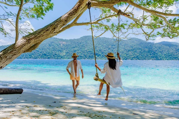 南タイのコラー島のビーチでロープスイングで遊ぶカップル タルタオ国立公園 コラウィ タンボンコTarutaoでターコイズブルーの海と熱帯の白い砂浜 — ストック写真