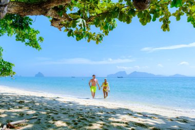 Koh Kradan Island Southern Thailand voted as the new nr 1 beach in the world. a couple of men and women walking on the tropical beach of Koh Kradan at ocean front clipart