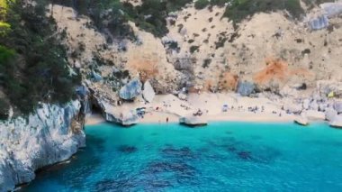 Cala Mariolu Plajı Sardinya İtalya, plaj şemsiyeleriyle dolu, güneşlenen ve turkuaz suda yüzen insanlarla dolu güzel bir plajdır. Cala Gonone Baunei, Sardinya, İtalya Golfo Di Orosei