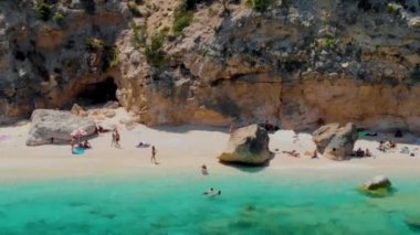 Cala Mariolu Plajı Sardinya İtalya, plaj şemsiyeleriyle dolu güzel bir plaj ve yaz aylarında güneş banyosu yapan ve turkuaz suda yüzen insanlar. Cala Gonone Baunei, Sardinya, İtalya Golfo Di Orosei