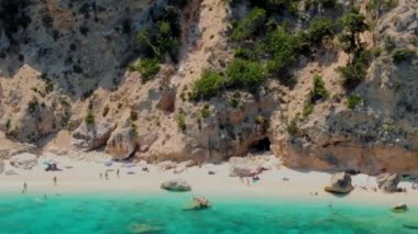 Cala Mariolu Plajı Sardinya İtalya, plaj şemsiyeleriyle dolu güzel bir plaj ve güneşlenen ve turkuaz suda yüzen insanlar. Yaz boyunca Cala Gonone Baunei, Sardinya, İtalya Golfo Di Orosei