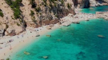 Cala Mariolu Plajı Sardinya İtalya, plaj şemsiyeleriyle dolu güzel bir plaj ve güneşlenen ve turkuaz suda yüzen insanlar. Yaz boyunca Cala Gonone Baunei, Sardinya, İtalya Golfo Di Orosei