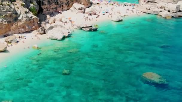 Cala Mariolu Beach Sardiniaイタリアは 夏にターコイズブルーの水で日光浴や水泳をするビーチ傘と人々でいっぱいの美しいビーチです Cala Gonone Baunei サルデーニャ島 イタリア — ストック動画