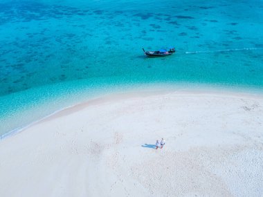 Tatil sırasında Koh Lipe Güney Tayland 'da bir kumsalda yürüyen erkekler ve kadınlar. Turkuaz renkli bir okyanusta kumsalda bir çift.
