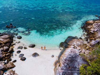 Kla Island Koh Lipe Thailand is a small island on the coast of Ko Lipe with a coral reef and great snorkeling place, couple men and women on the beach seen from a drone view clipart