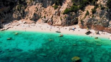 Cala Mariolu Plajı Sardinya İtalya, plaj şemsiyeleriyle dolu, güneşlenen ve turkuaz suda yüzen insanlarla dolu güzel bir plajdır. Cala Gonone Baunei, Sardinya, İtalya Golfo Di Orosei