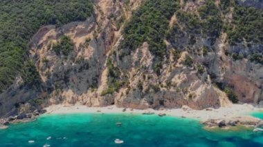 Cala Mariolu Plajı Sardinya İtalya, plaj şemsiyeleriyle dolu güzel bir plaj ve yaz aylarında güneş banyosu yapan ve turkuaz suda yüzen insanlar. Cala Gonone Baunei, Sardinya, İtalya Golfo Di Orosei