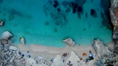 Yaz boyunca Cala Goloritze plajı, Baunei, Sardinya, İtalya Golfo Di Orosei Cala Gonone, plajın yukarısından güneşlenen insanlarla insansız hava aracı manzarası