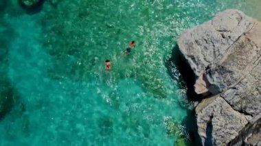 İtalya 'nın Sardunya sahillerinde erkek ve kadınlar, okyanusta kristal mavisi su ile oynayan birkaç erkek ve kadın Cala Luna Sardunya İtalya' da Golfo Di Orosei 'de şnorkelle yüzüyor.