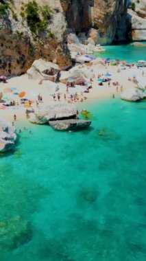 Cala Mariolu plajı, Cala Biriola ve Cala Goloritze yakınları, Baunei, Sardinya, İtalya yaz boyunca insanlar çakıl taşı plajında güneşlenirken
