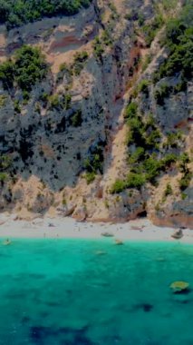 Yaz boyunca Cala Goloritze plajı, Baunei, Sardinya, İtalya Golfo Di Orosei Cala Gonone, plajın yukarısından güneşlenen insanlarla insansız hava aracı manzarası