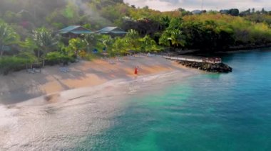 Gün batımında plajda yürüyen bir çift erkek ve kadın yukarıdan St. Lucia Tropikal Adası 'ndaki Saint Lucia Castries plajında