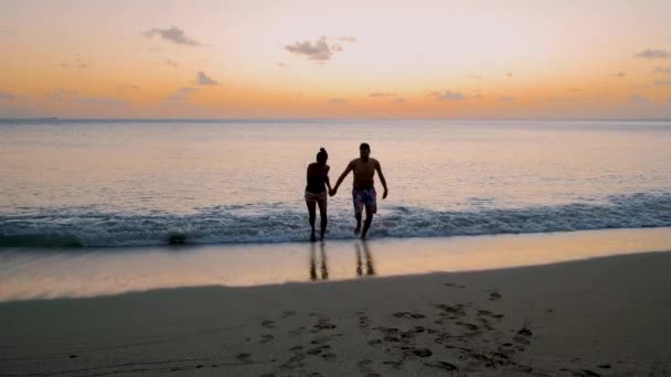 サンルシアのビーチ豪華なホテル 日没時に青いタークス色の海を持つセントルシアの熱帯の島 夕暮れ時に男と女のカップルがビーチを歩く — ストック動画
