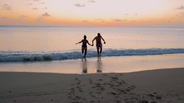 日没時に青いターコイズブルーの海とセントルシアまたはセントルシアの熱帯島 数人の男女が日没時にビーチを歩いている — ストック動画