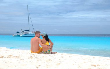 Küçük Curacao Adası 'na tekne gezisine giden birkaç erkek ve kadın. Beyaz bir plaj ve turkuaz renkli bir okyanus.
