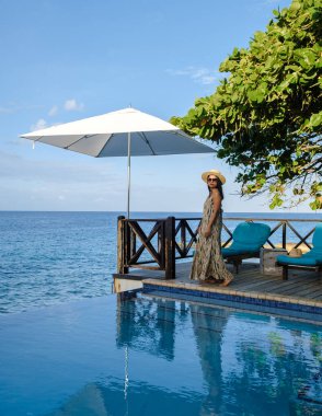 Orta yaşlı bir kadın tatil sırasında havuz kenarında dinleniyor. Tatil sırasında Curacao 'da havuz kenarında tropikal bir adada lüks bir tatil yapıyor.