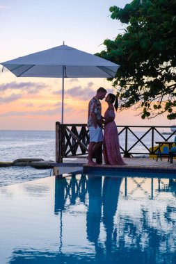 Bir çift orta yaşlı erkek ve kadın tatilde yüzme havuzunda dinleniyorlar, erkekler ve kız Curacao 'da tatil sırasında tropik bir adada lüks bir tatil yapıyorlar.