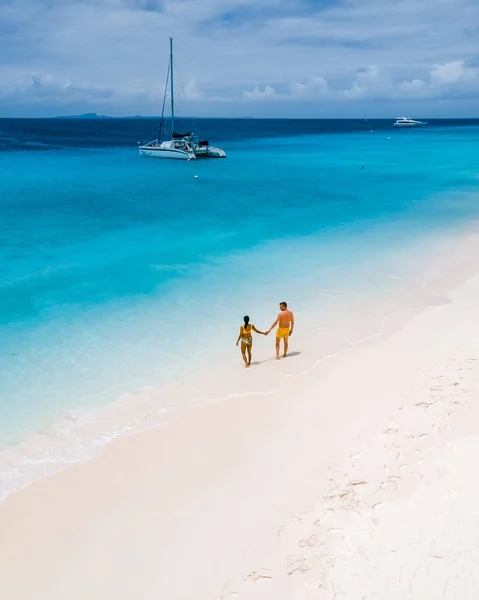 在乘船前往拥有白色海滩和草皮色海洋的库拉索岛的途中 一对男女在白色热带海滩上的无人驾驶航空图像 — 图库照片