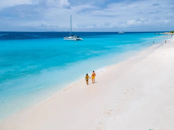 白いビーチとターコイズ色の海と小さなキュラソー島へのボート旅行中に白い熱帯のビーチで数人の男性と女性の無人航空機の景色 — ストック写真