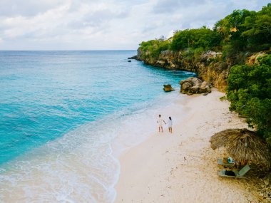 Playa Kalki Plajı Karayip adası Curacao, mavi turkuaz renkli okyanuslu beyaz plaj. Kumsaldaki bir çift kadın ve erkeğin hava görüntüsü.