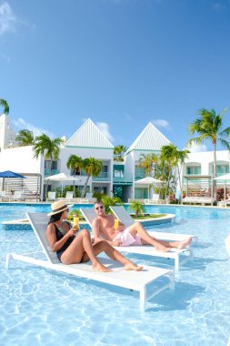 Palm Beach yakınlarında yüzme havuzu olan lüks tatil köyü Aruba Karayipleri, yaz boyunca Karayipler 'de lüks bir tatil yapan orta yaşlı çift.