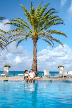 Palm Beach yakınlarında yüzme havuzu olan lüks tatil köyü Aruba Karayipleri, yaz boyunca Karayipler 'de lüks bir tatil yapan orta yaşlı çift.