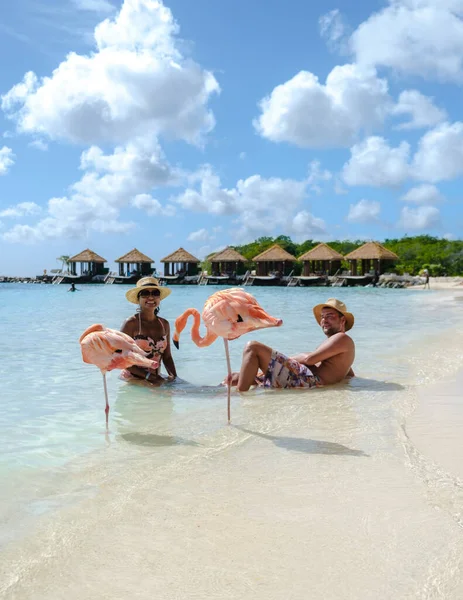 ビーチでピンクのフラミンゴを持つアルバビーチ 夏休み中にアルバ島カリブ海でピンクのフラミンゴを持つビーチで男女のカップル — ストック写真