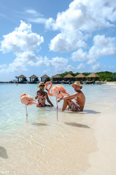 ビーチでピンクのフラミンゴを持つアルバビーチ 夏休み中にアルバ島カリブ海でピンクのフラミンゴを持つビーチで男女のカップル — ストック写真