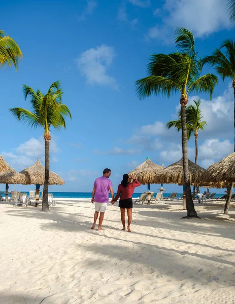 パームビーチアルバ カリブ海は 休暇中にアルバ アンティルにヤシの木がある白い長い砂浜の男性と女性のカップルです — ストック写真