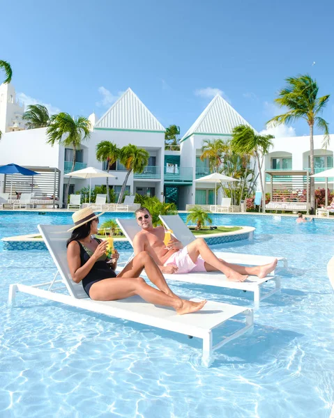 리조트에는 아루바 카리브 수영장 있으며 남녀가 카리브해에서 여행을 — 스톡 사진