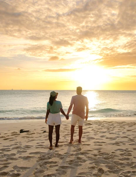 アルバ島での休暇中に夕日を見ているビーチには男性と女性のカップルがいますカリブ海 — ストック写真