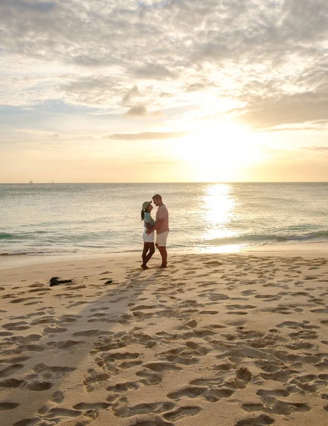 アルバ島のカリブ海での休暇中に夕日を見ているビーチには数人の男性と女性がいます ビーチでの成熟したカップルは — ストック写真