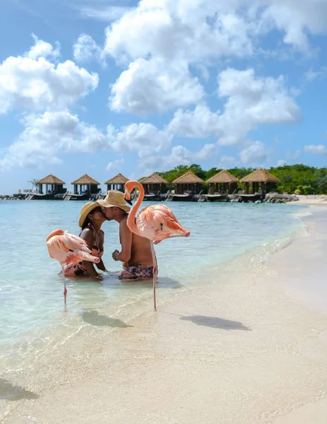 ビーチでピンクのフラミンゴを持つアルバビーチ 休暇中にアルバ島カリブ海でピンクのフラミンゴを持つビーチで男女のカップル — ストック写真