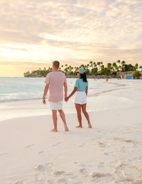 两名男子和妇女在阿鲁巴加勒比岛屿度假期间正在海滩观看日落 在超级网中 男人和女人在海洋边 — 图库照片