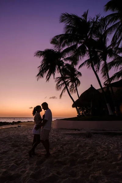 アルバ島のカリブ海での休暇中に夕日を見ているビーチには数人の男性と女性がいます スネット時代の海の男と女 — ストック写真