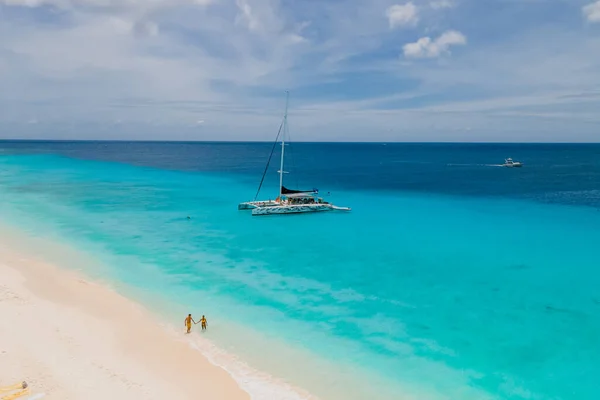 在阳光明媚的日子里 一对男女正在乘船前往小岛库拉索岛 那里有一个白色的海滩和草皮色的大海 — 图库照片