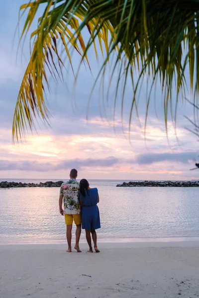 夕暮れ時のキュラソー島のビーチでのカップル 休暇中のキュラソー島の熱帯ビーチで夕日を見る男性と女性 — ストック写真